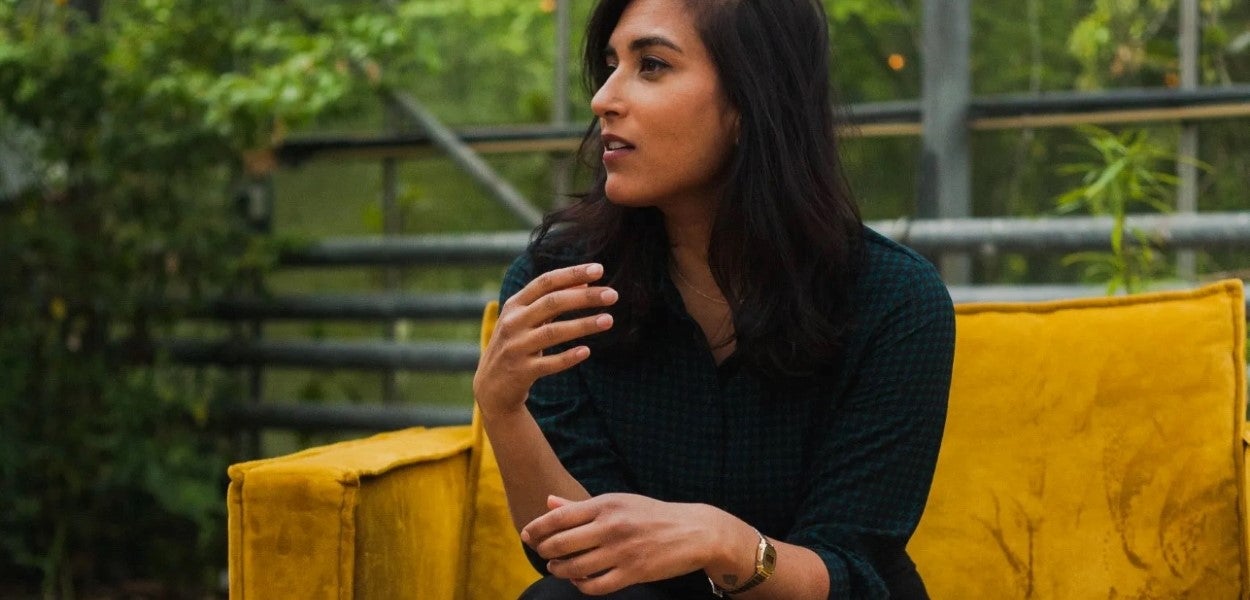 Siema Ramdas sits on a yellow bench in an indoor garden