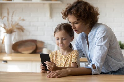 Een vrouw en een meisje die naar een telefoon kijken