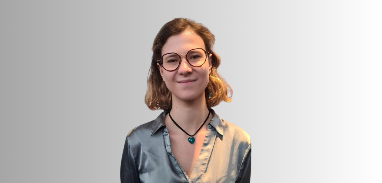 Michaela Kaneva poses in front of a white wall.