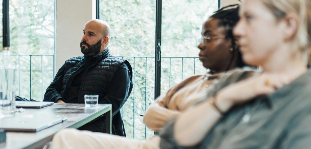 People at a table listening intently to a speaker