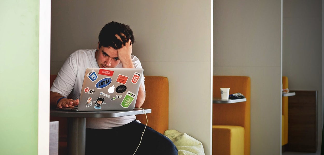 A student sits in front of his laptop frustrated 