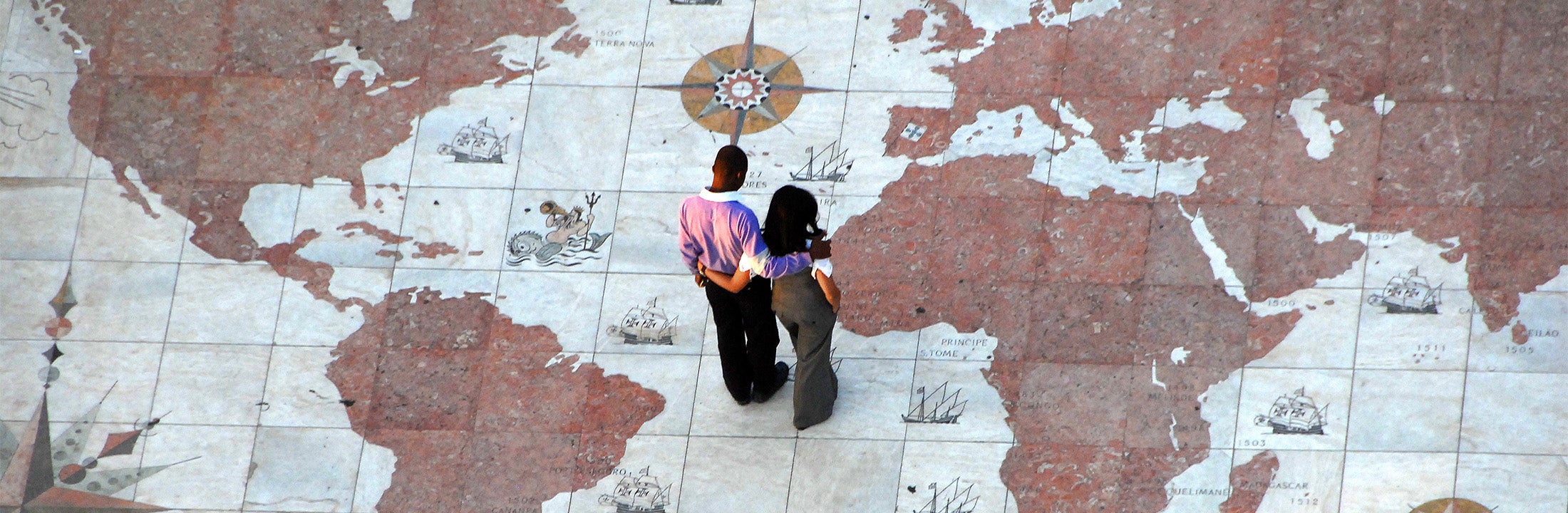 A man and a woman are standing on a monument in Lissabon that marks the main routes of the Portuguese expansion 