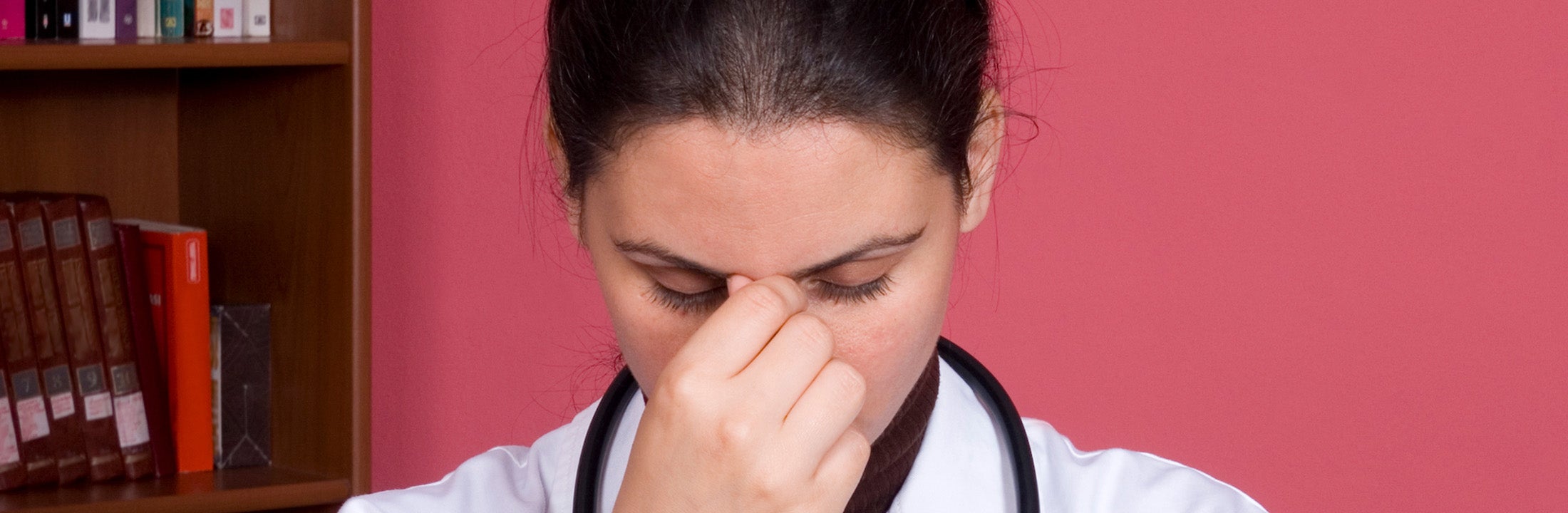 Vrouw in doktersjas met hand op het gezicht