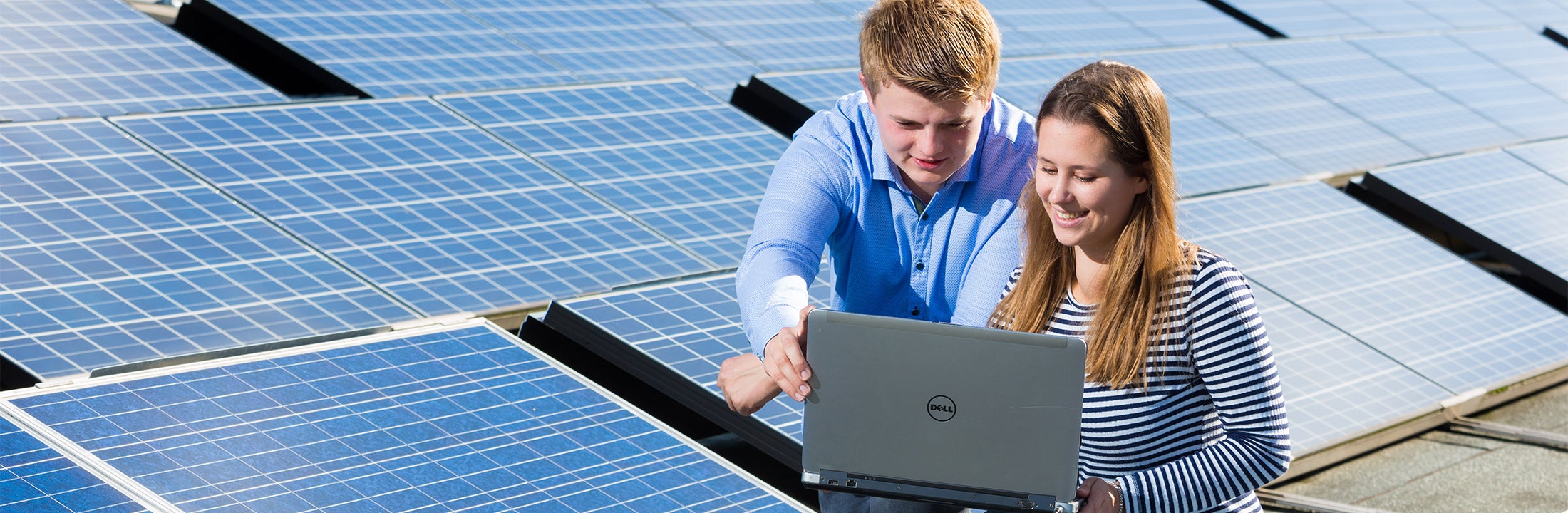 Two students surrounded by solar panels