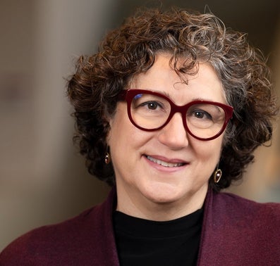 A woman with glasses and a purple jacket