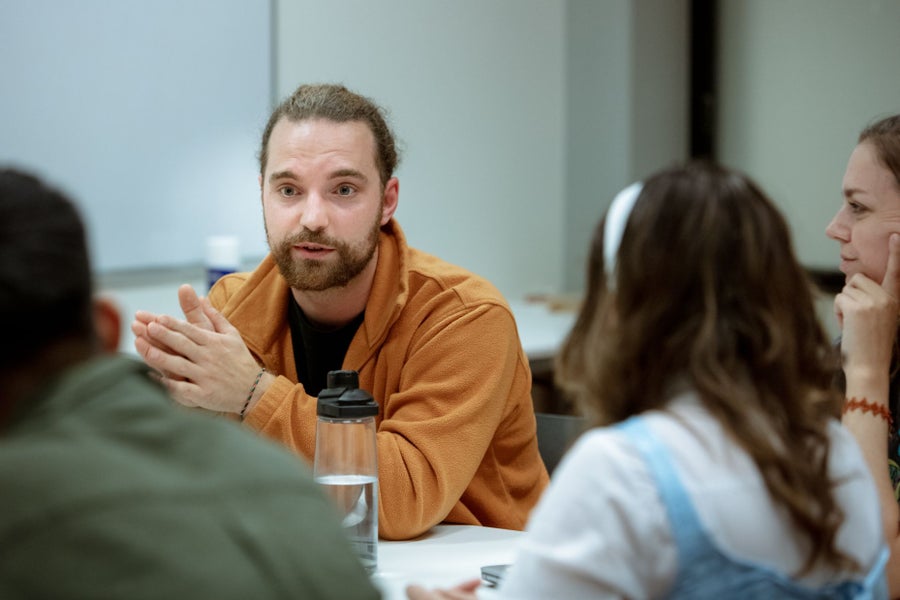 A man sitting at a table talking to people.