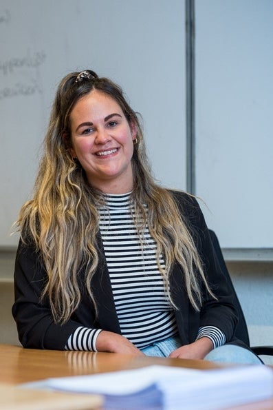 Lachende Faye Best achter het bureau in haar klaslokaal