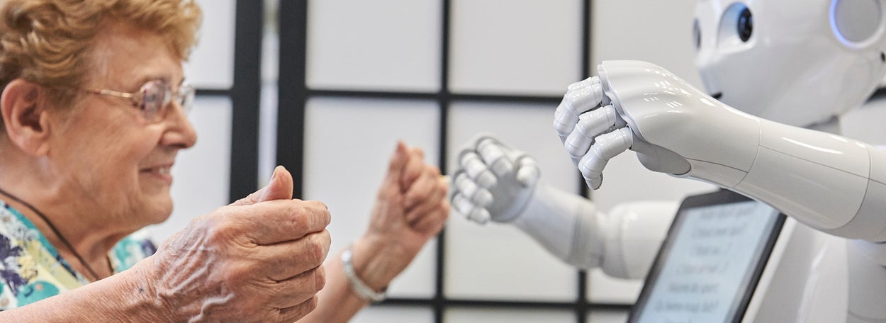 Elderly woman is having a conversation with a white robot