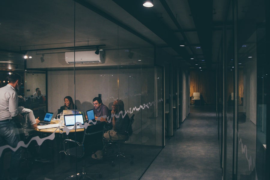 A group of people sitting at a table with laptops