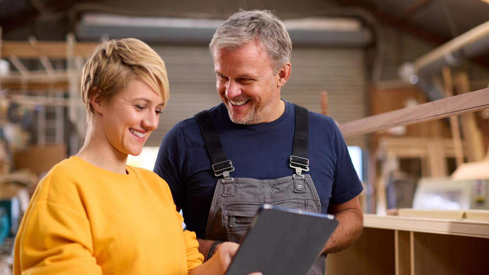 Two workers in a workshop looking at a tablet device