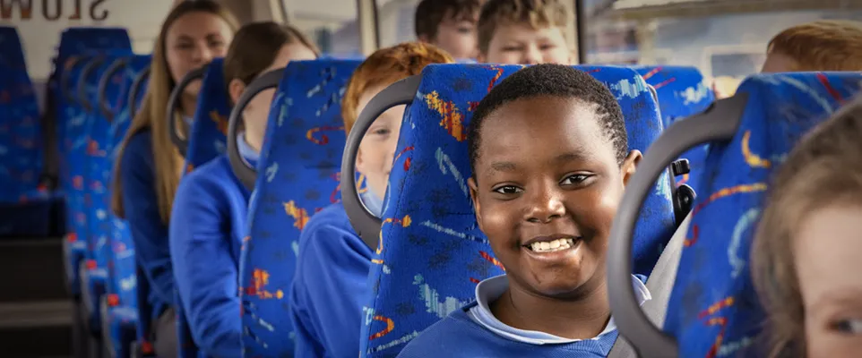 Photograph of school children sitting on a bus.