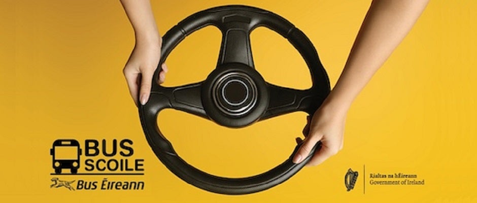 A close-up image features a black steering wheel held by two hands against a bright yellow background.