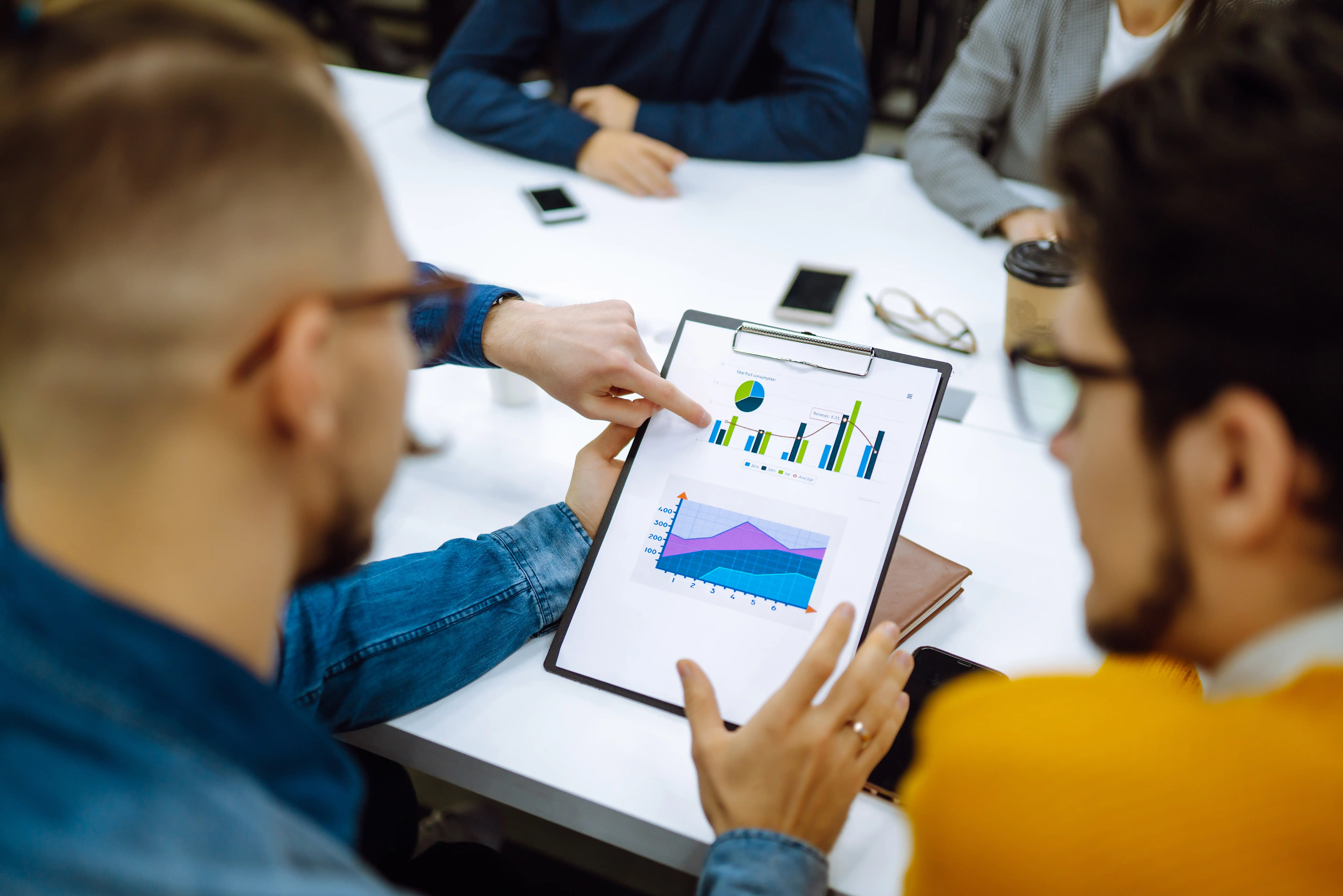 Equipo de profesionales en una agencia de marketing digital analizando reportes en una sala de reuniones.