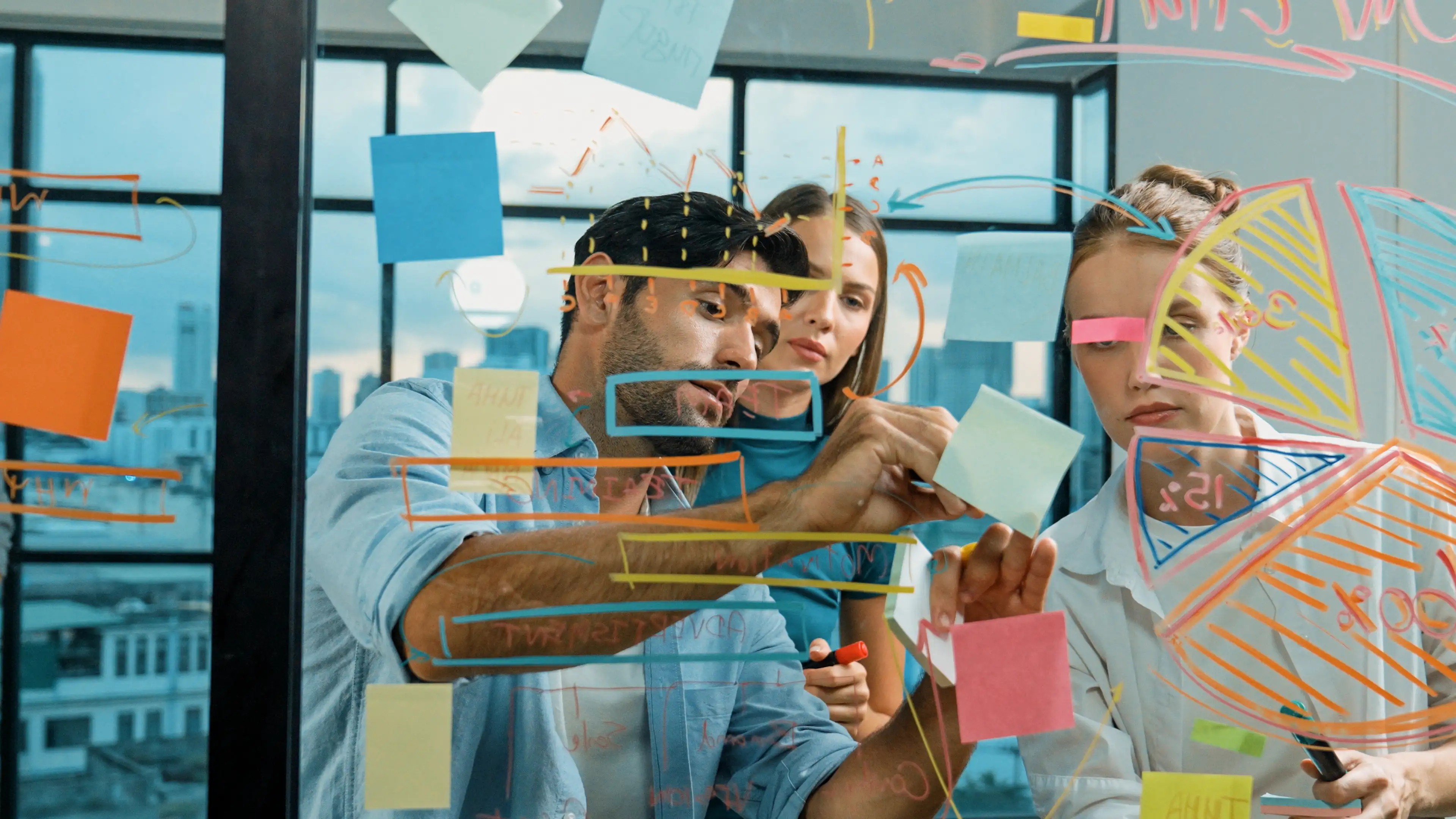 Equipo de marketing trabajando en el análisis de datos mientras anotan ideas en post-it.