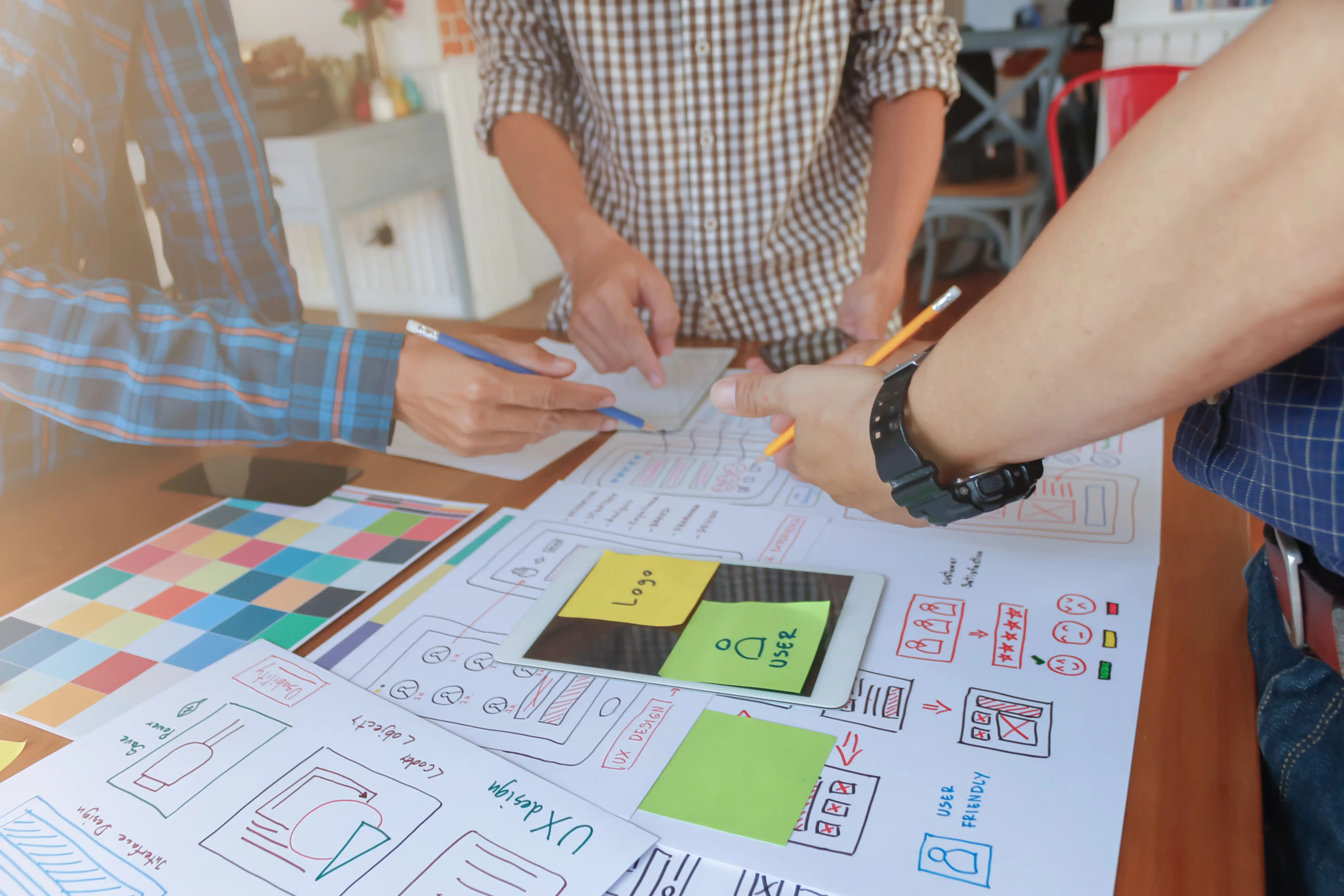 Equipo de diseñadores web trabajando en componentes para el sitio, mostrando un flujo de trabajo modular al que le van añadiendo "piezas" (post it).