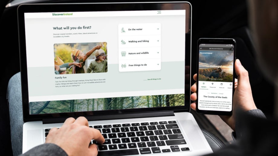 Man browsing the Discover Ireland website on laptop and mobile phone.