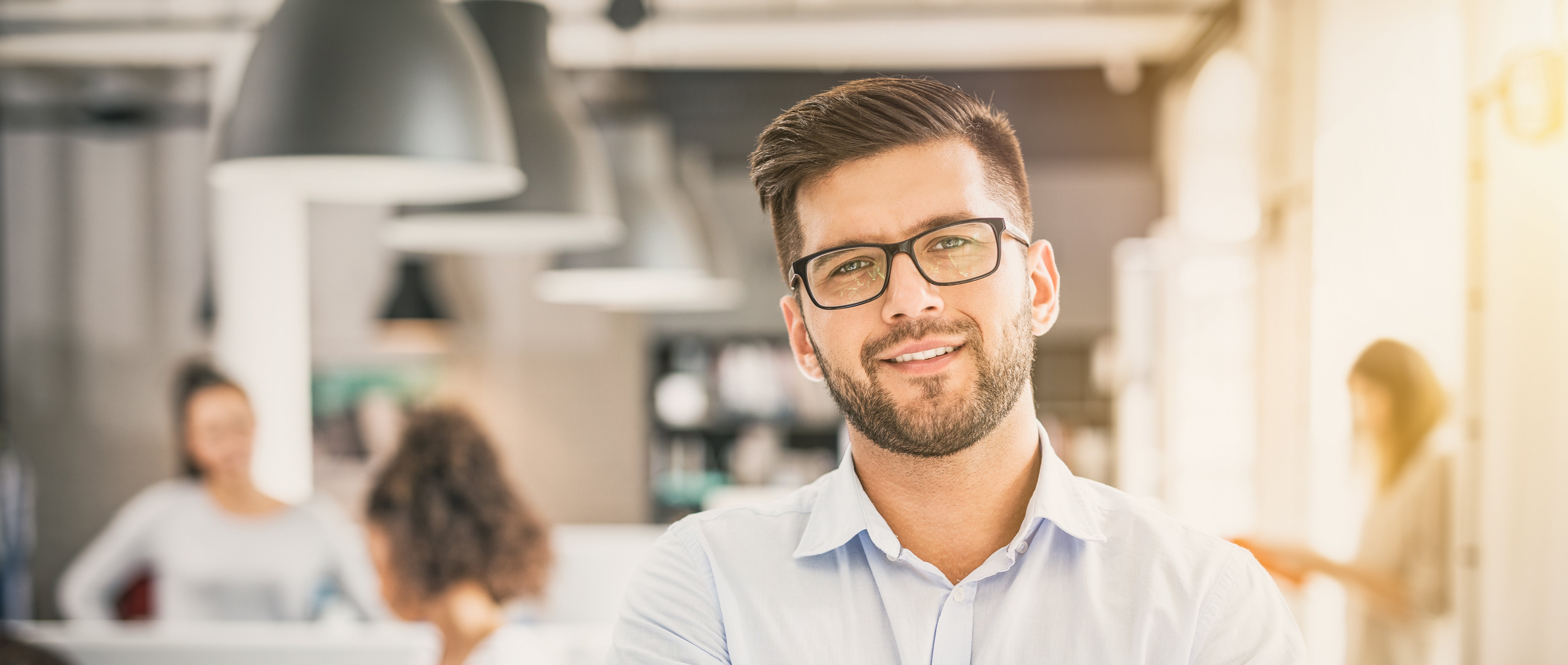 businessman smiles with coworkers in the background
