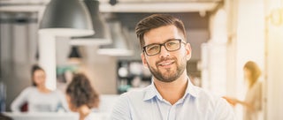 businessman smiles with coworkers in the background