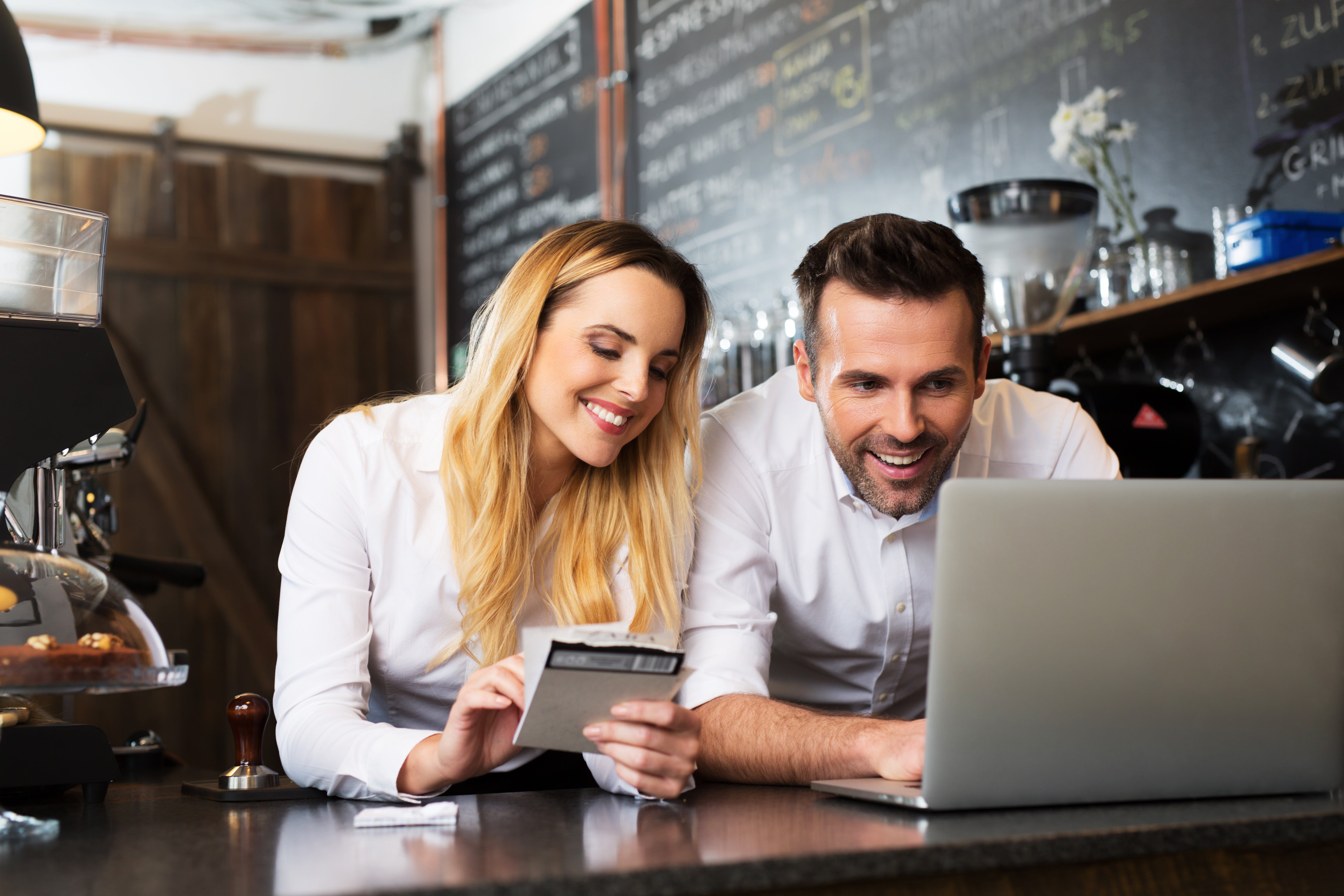 Two business owners and computer in coffee shop