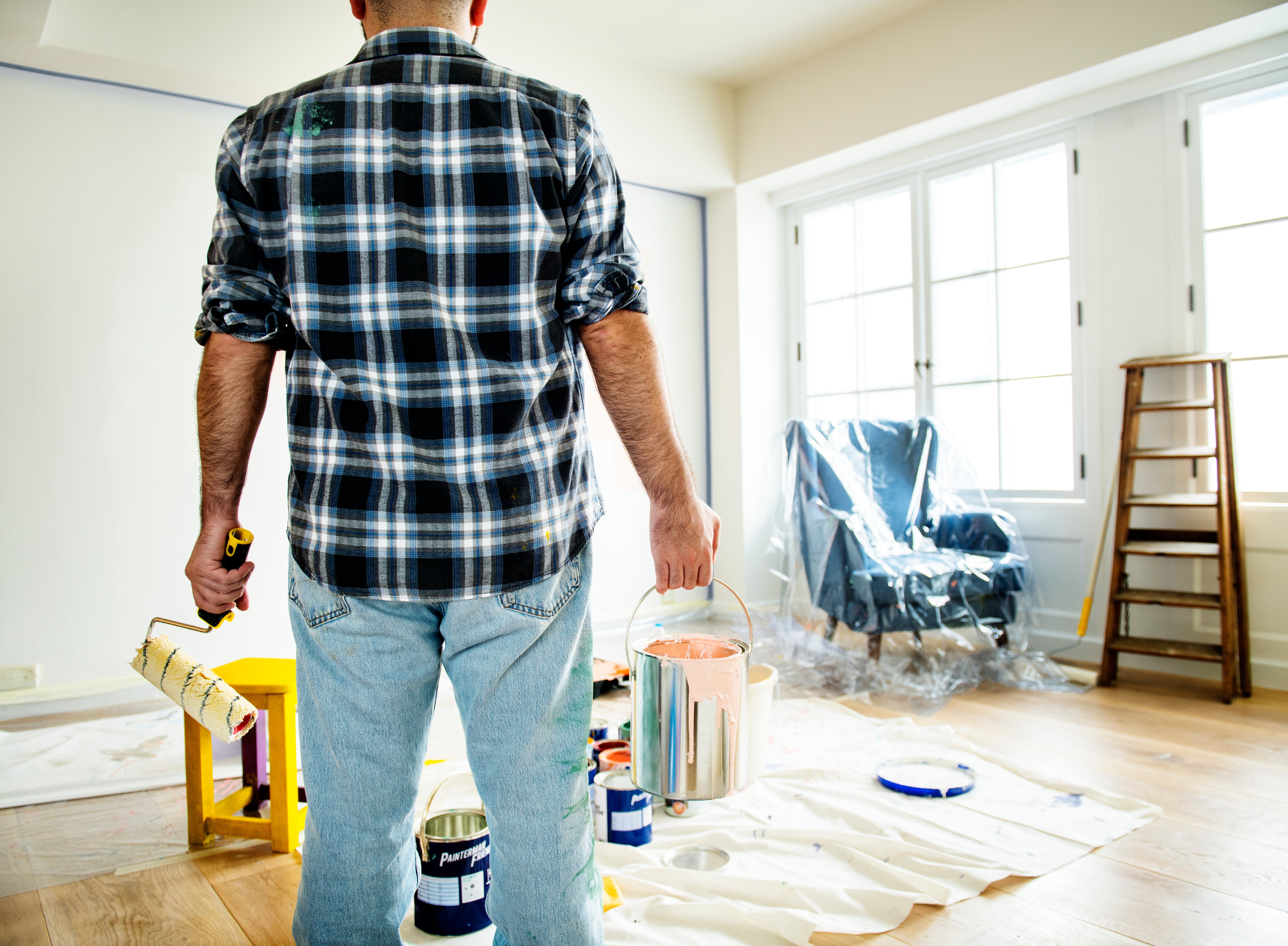Man holding paint bucket and roller brush