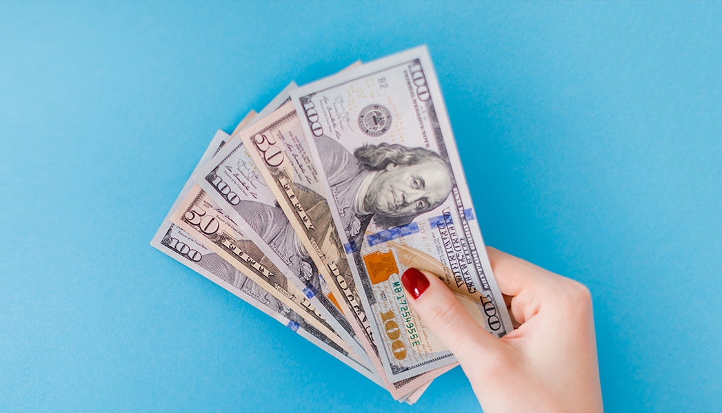 Hand holding large amounts of cash