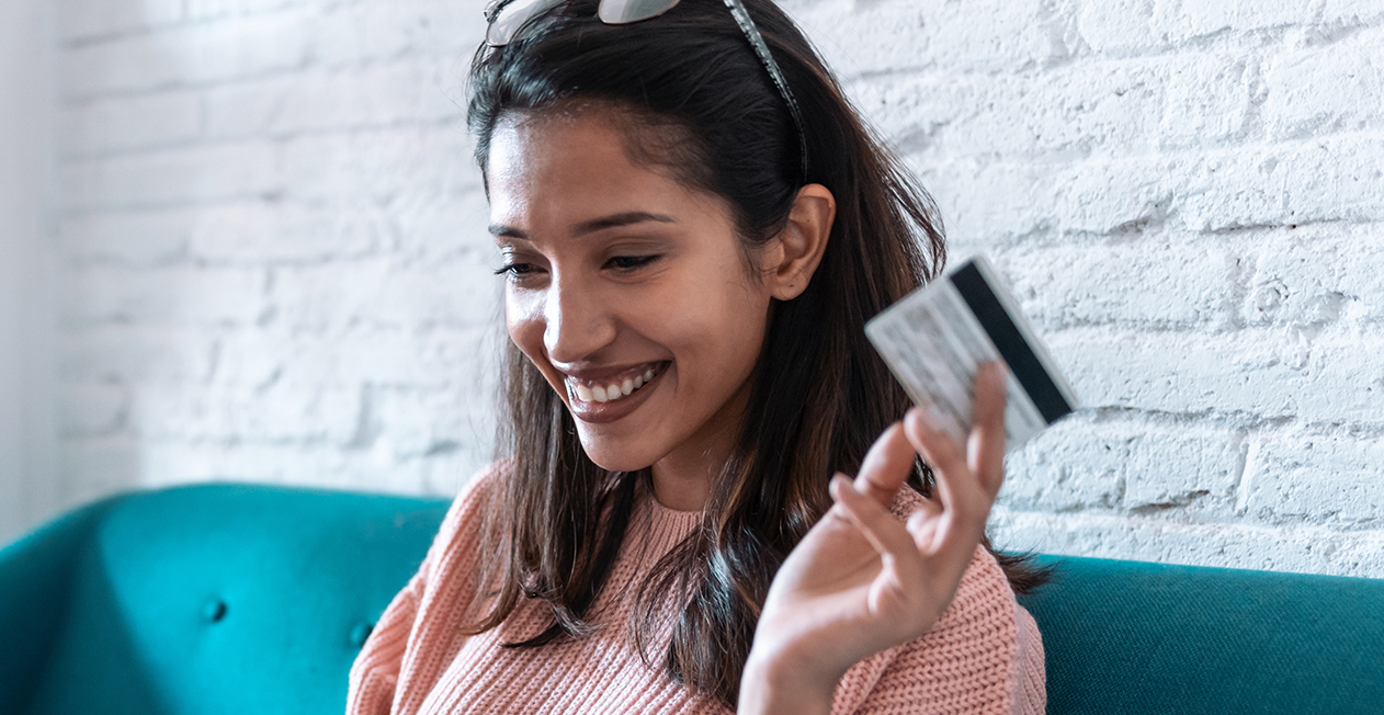 Woman holds credit card while smiling