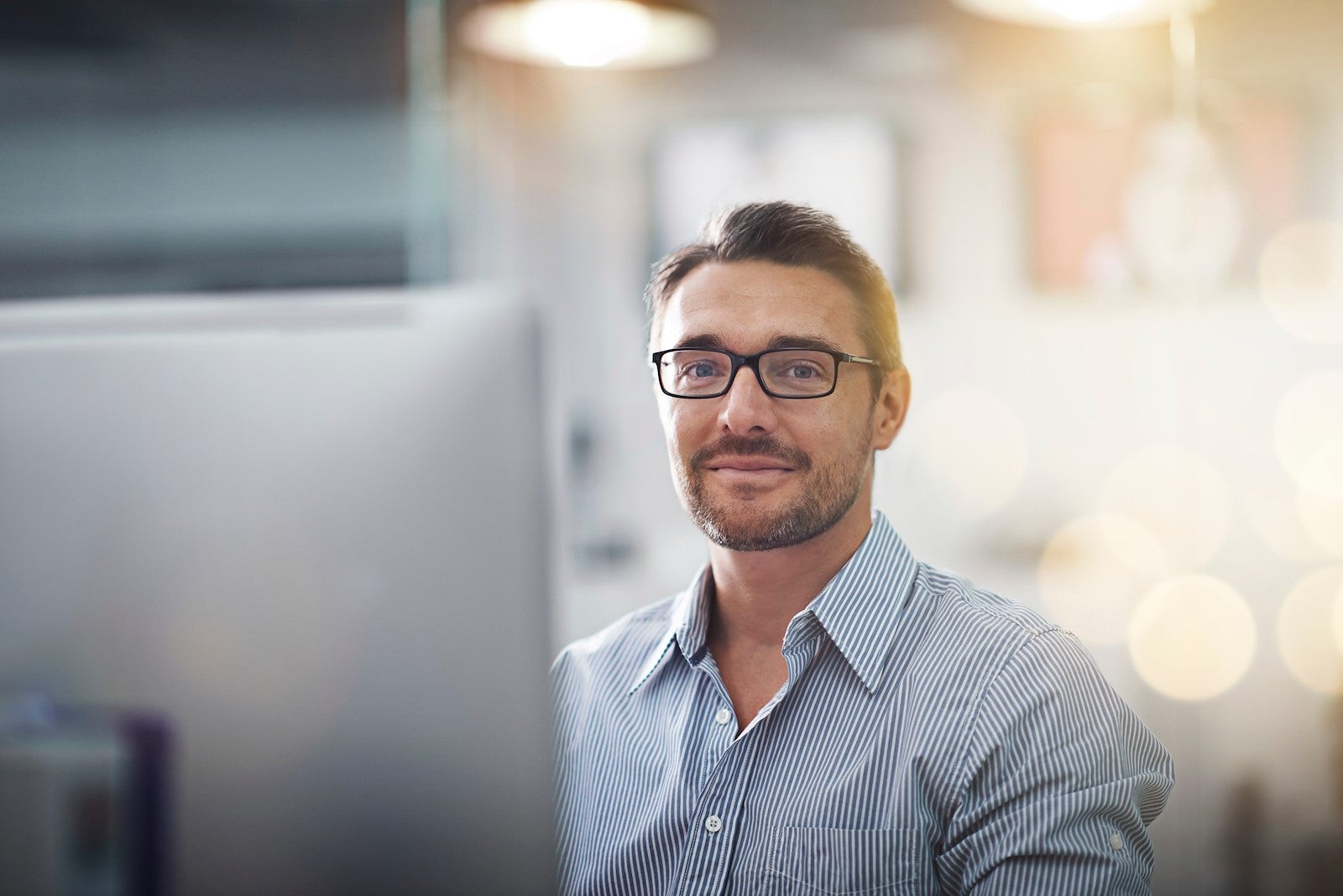 Man sits behind computer smiling