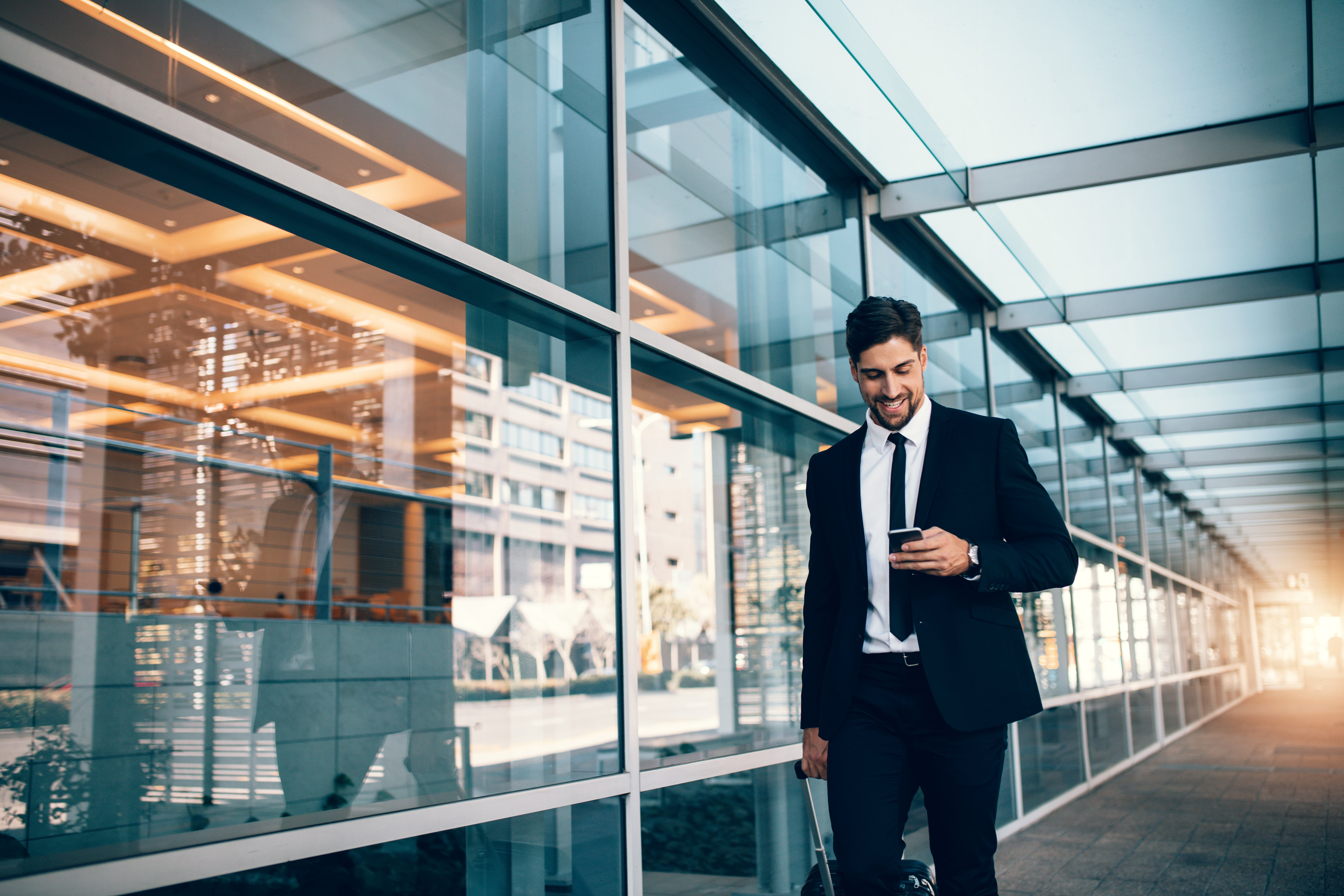 Businessman looks at phone while walking