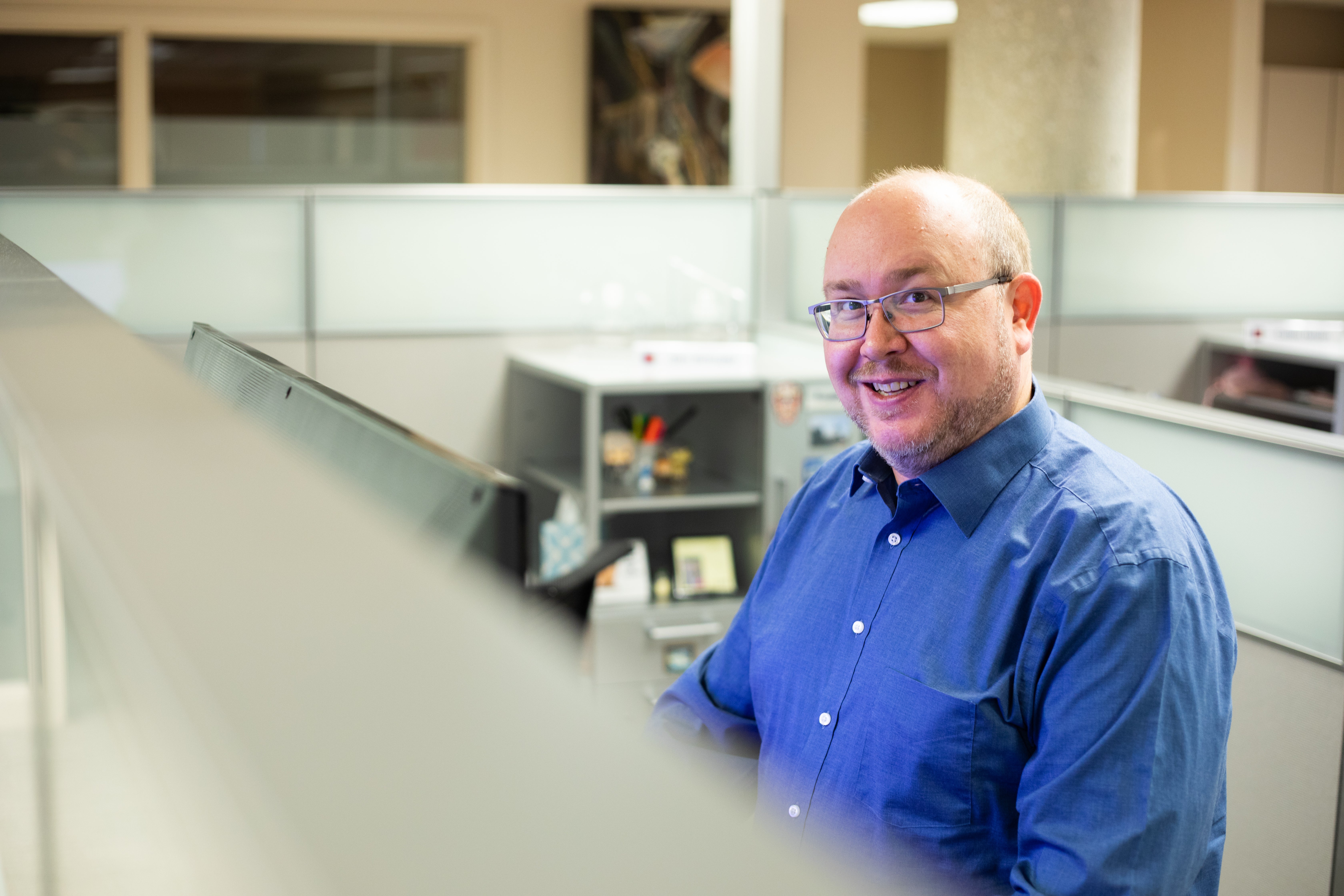 Technology associate smiles in blue shirt