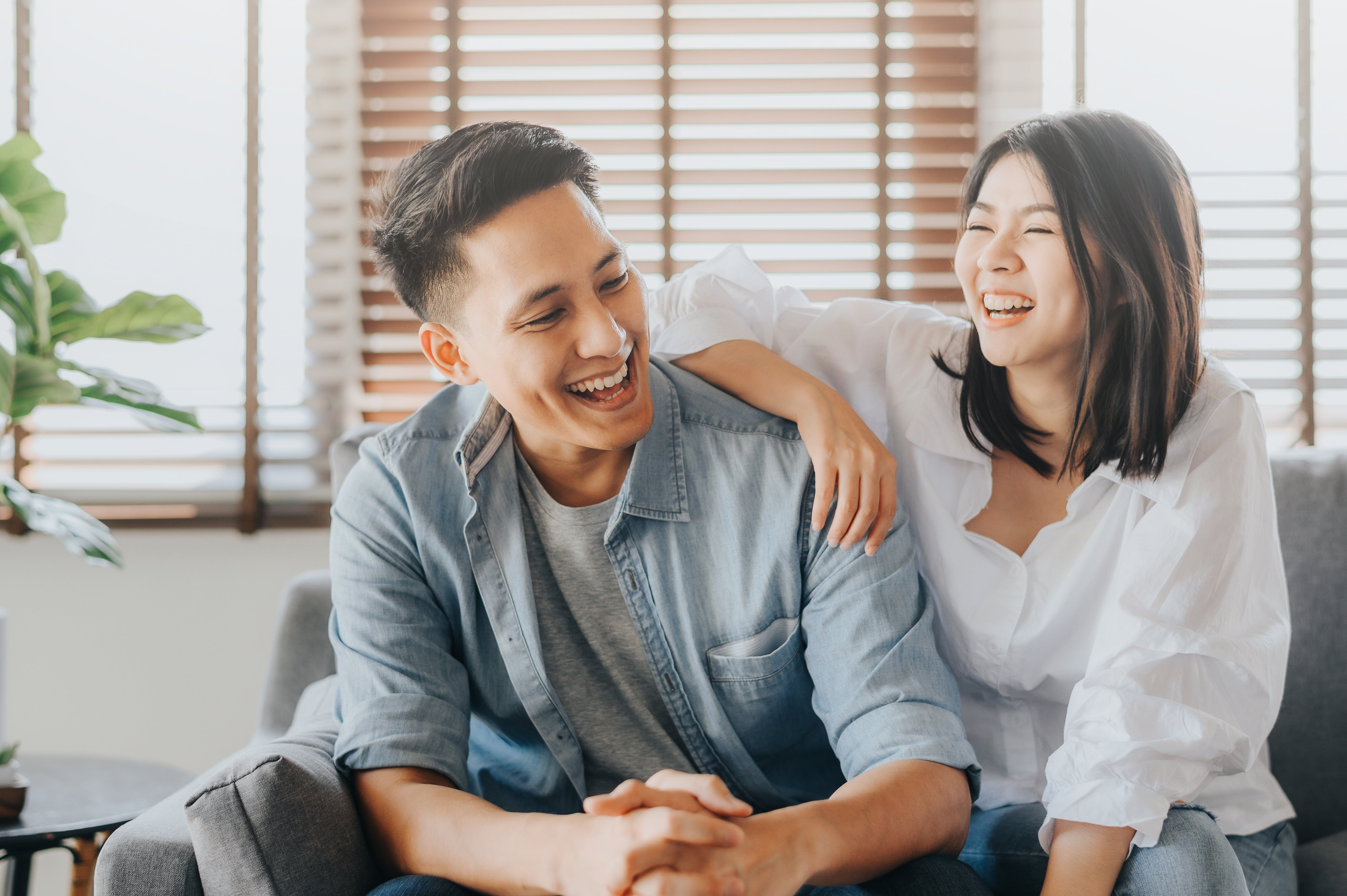 Couple laughing while sitting on couch