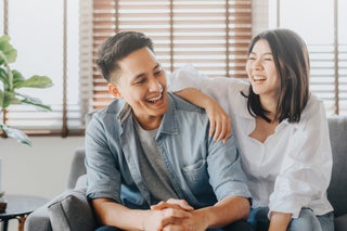 Couple laughing while sitting on couch
