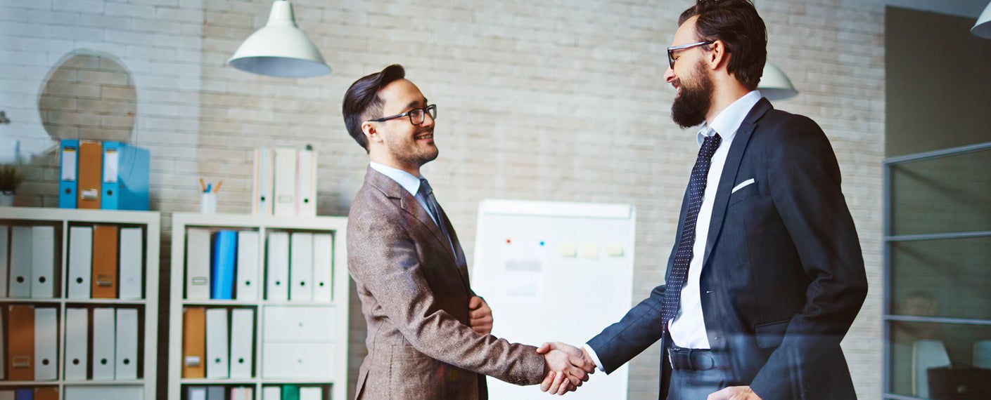 Two businessmen shake hands in an office