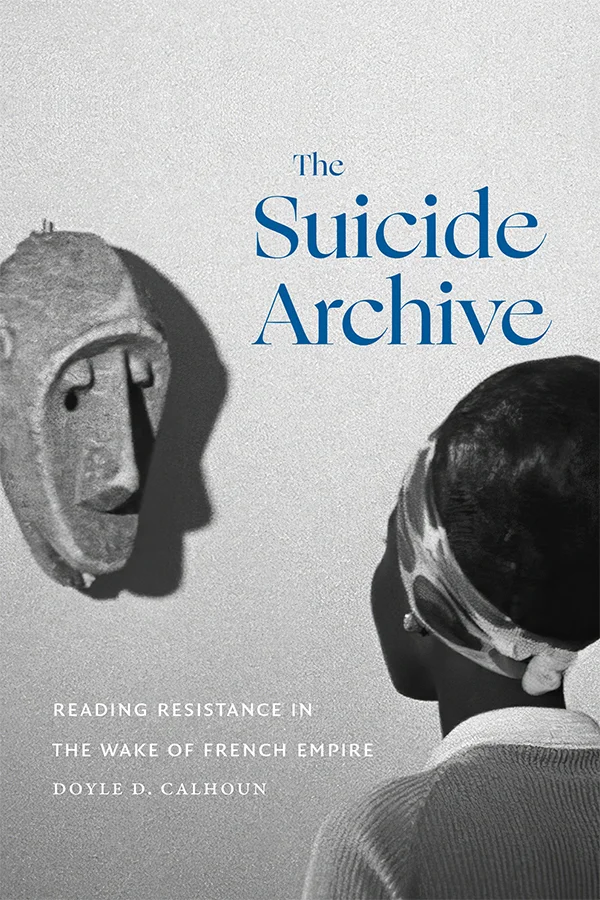 Cover of The Suicide Archive: Reading Resistance in the Wake of French Empire by Doyle D. Calhoun. Cover features an image of a woman staring forward, with only the back of her head facing the audience. She looks towards a mask which hangs on the wall in front of her. The mask casts a shadow on the wall. The title lettering is in blue, contrasted against the white of the wall on the cover.
