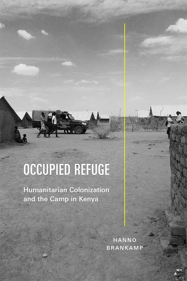 Cover of Occupied Refuge features a black-and-white photograph of a refugee camp with small structures that have corrugated metal roofs. In the foreground, a dirt ground stretches across the image with people walking, sitting, and standing near a veh