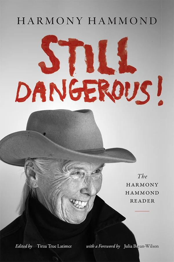 Cover of Still Dangerous! features a photograph of Harmony Hammond wearing a cowboy hat and smiling.