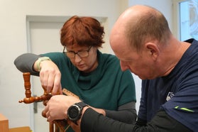 A woman (Ines) and a man (Tomáš) manipulating a wooden piece of the set.