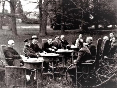 A photo of the Pátečníci meeting outside, with them all sitting in rocking chairs around small round tables.