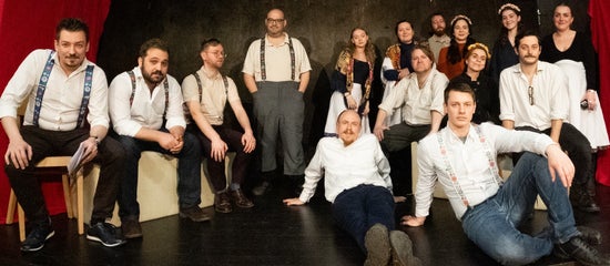 The entire cast spread out across a stage.