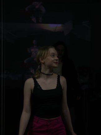 A woman in a lacy top smiles in a dark room.