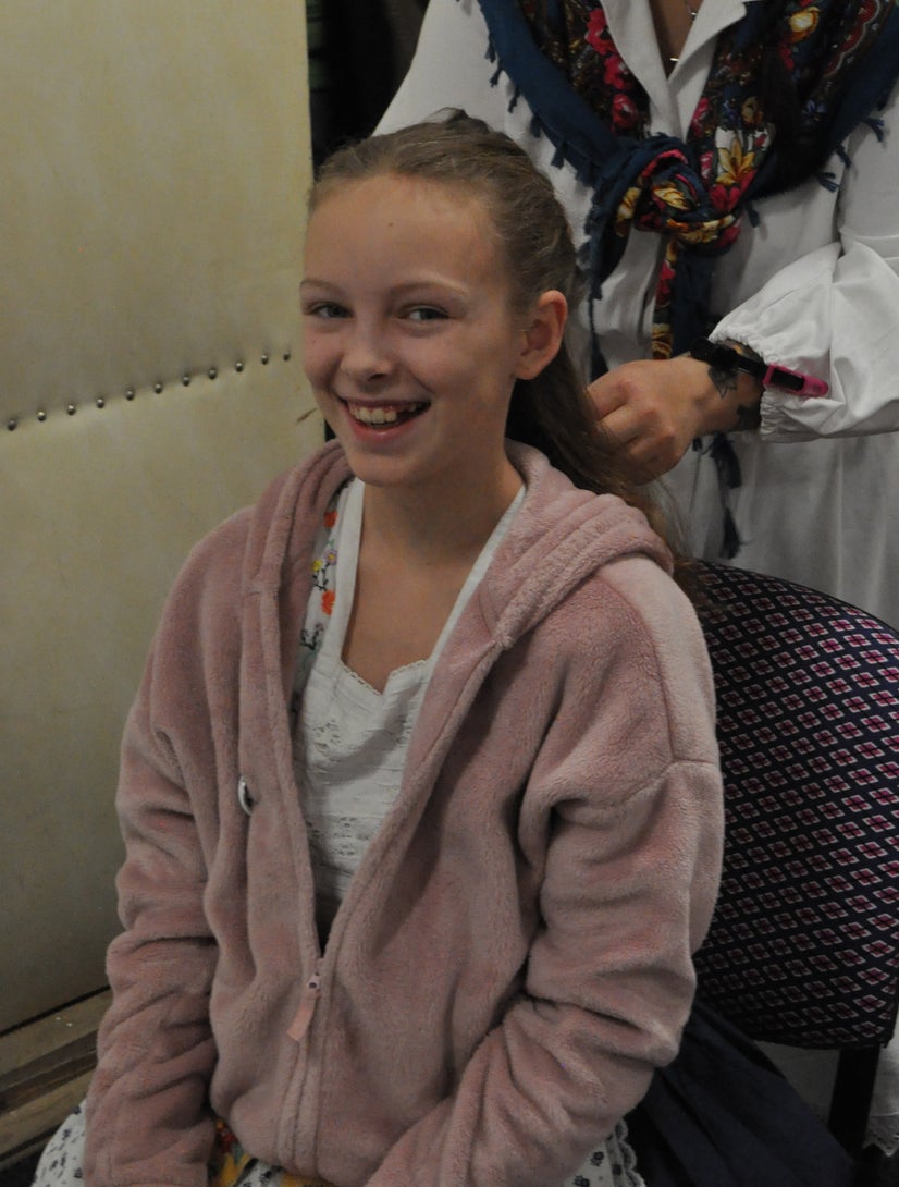 A girl smiling while she has her hair done.