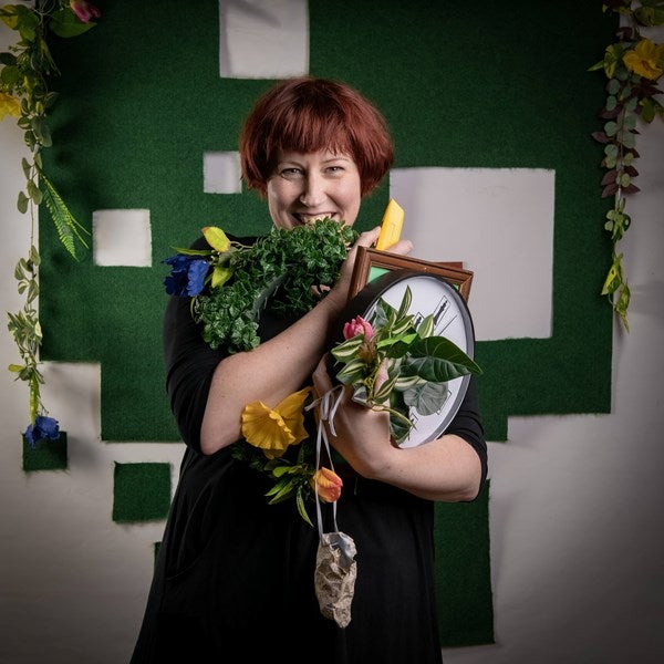 The set designer holds up and partly hides behind many props.