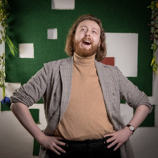 An actor gives a big laugh with his hands on his hips.