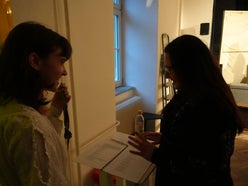 Two women laughing backstage in a dark room.