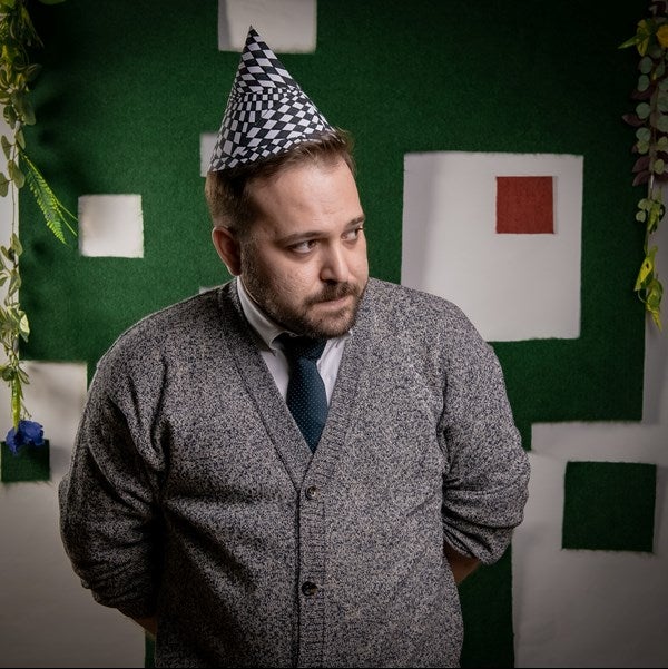 An actor in a party hat looks away from the camera.