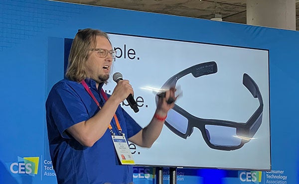 man speaking in front of XanderGlasses on screen