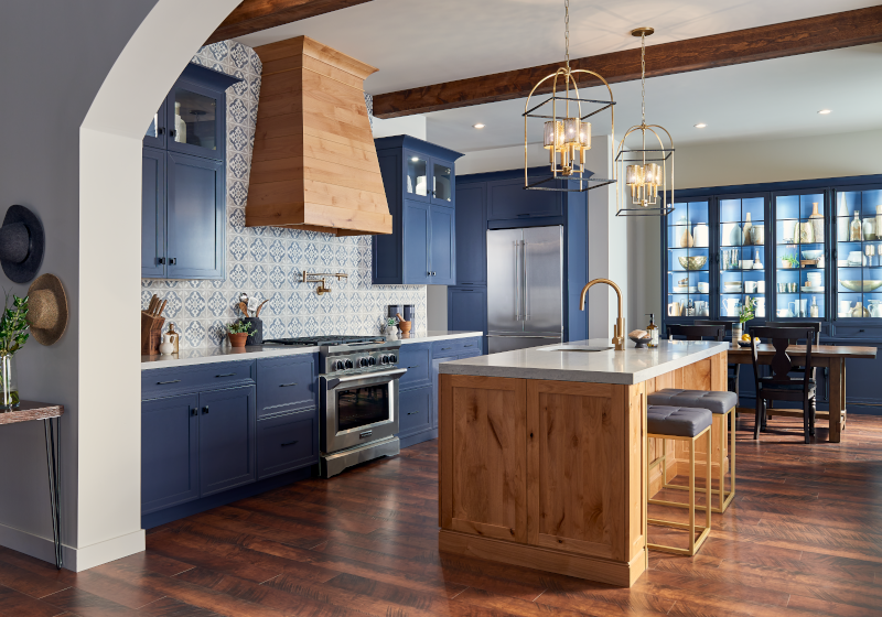 A kitchen featuring wood stained and painted cabinets, an island, and ample lighting.