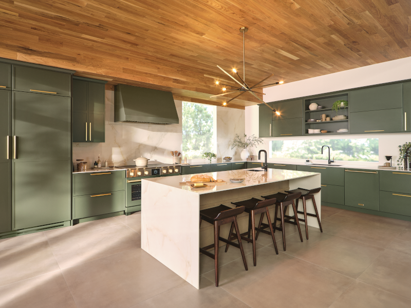 A kitchen with green kitchen cabinets, minimalist island, and modern lighting.