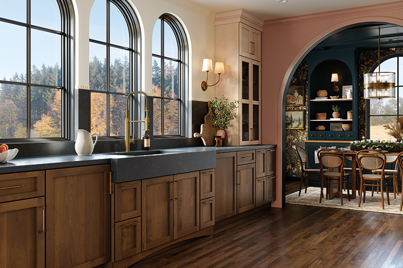 A kitchen with a large window, dark stained wood cabinets and floors, and a dining table.
