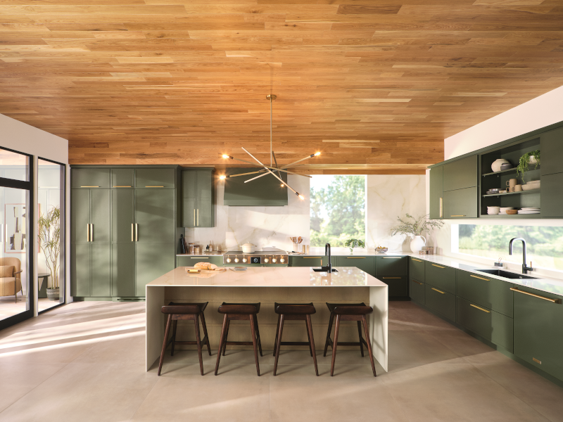 A kitchen that contains green kitchen cabinets and several windows.