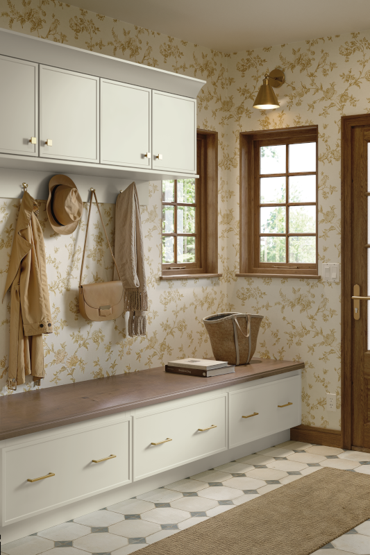A mudroom adjoining the kitchen with organized storage, hooks for coats, a bench seat, and beautiful, nature-inspired wallpaper.